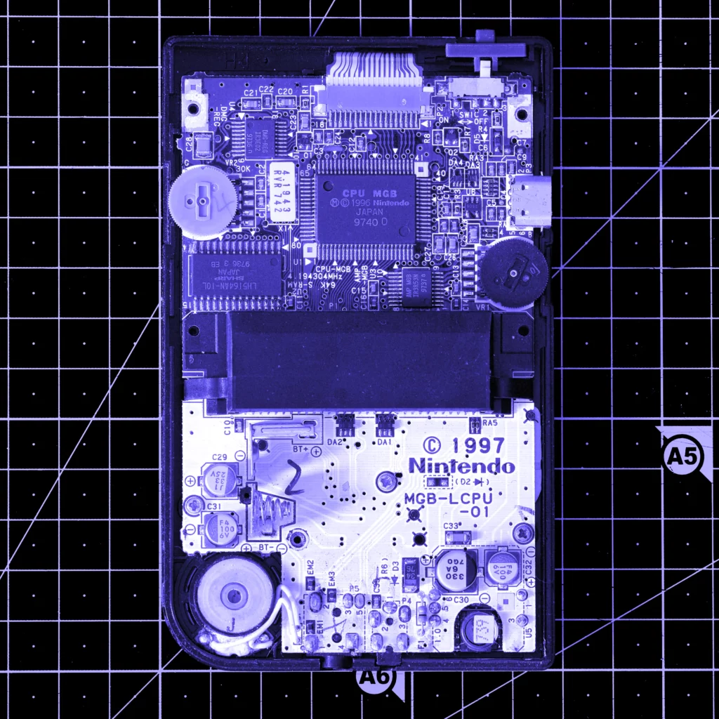 Photo du circuit imprimé d’une GameBoy Pocket sur une planche a découper «blueprint»