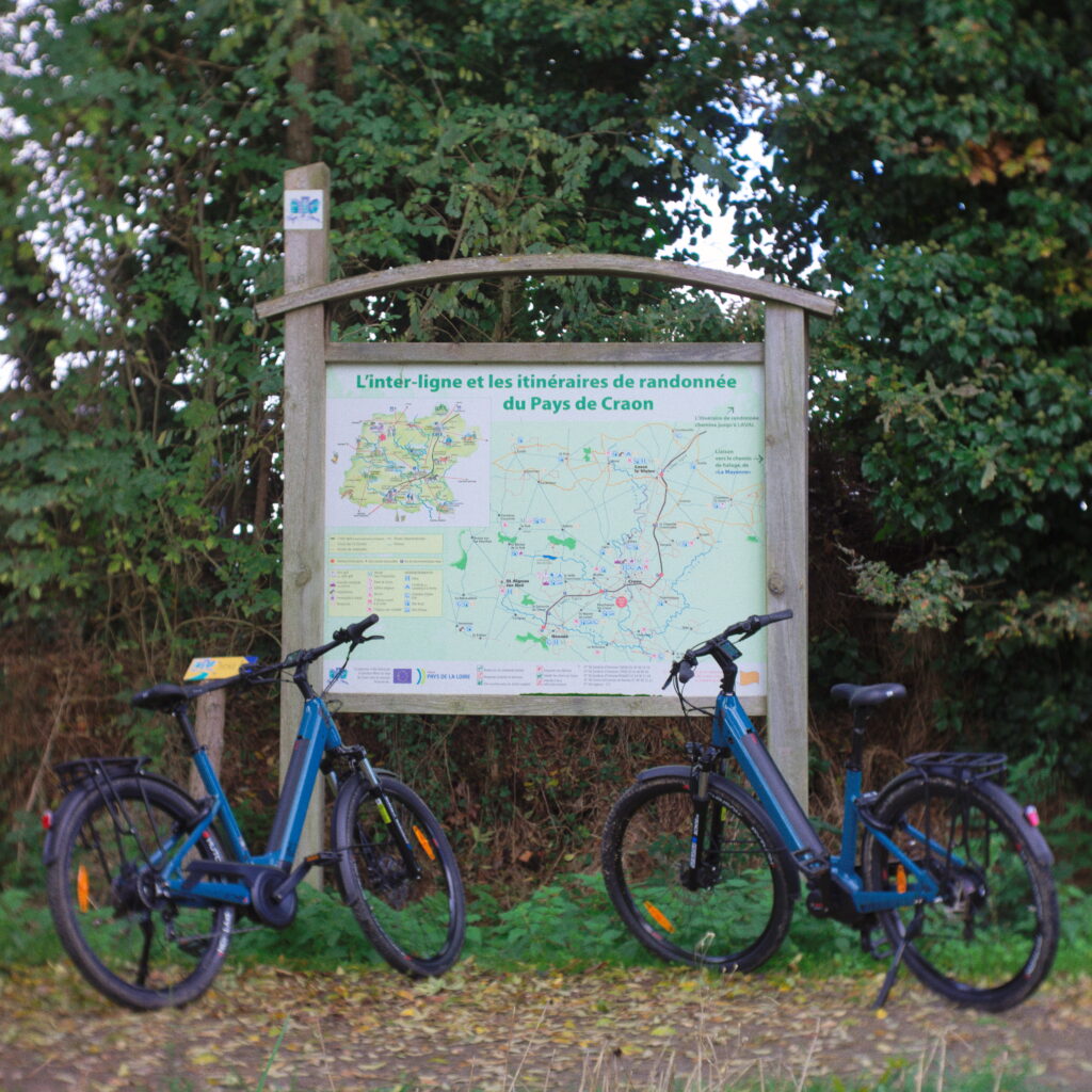 Photo de deux vélos électrique devant un panneau carte de l’itinéraire