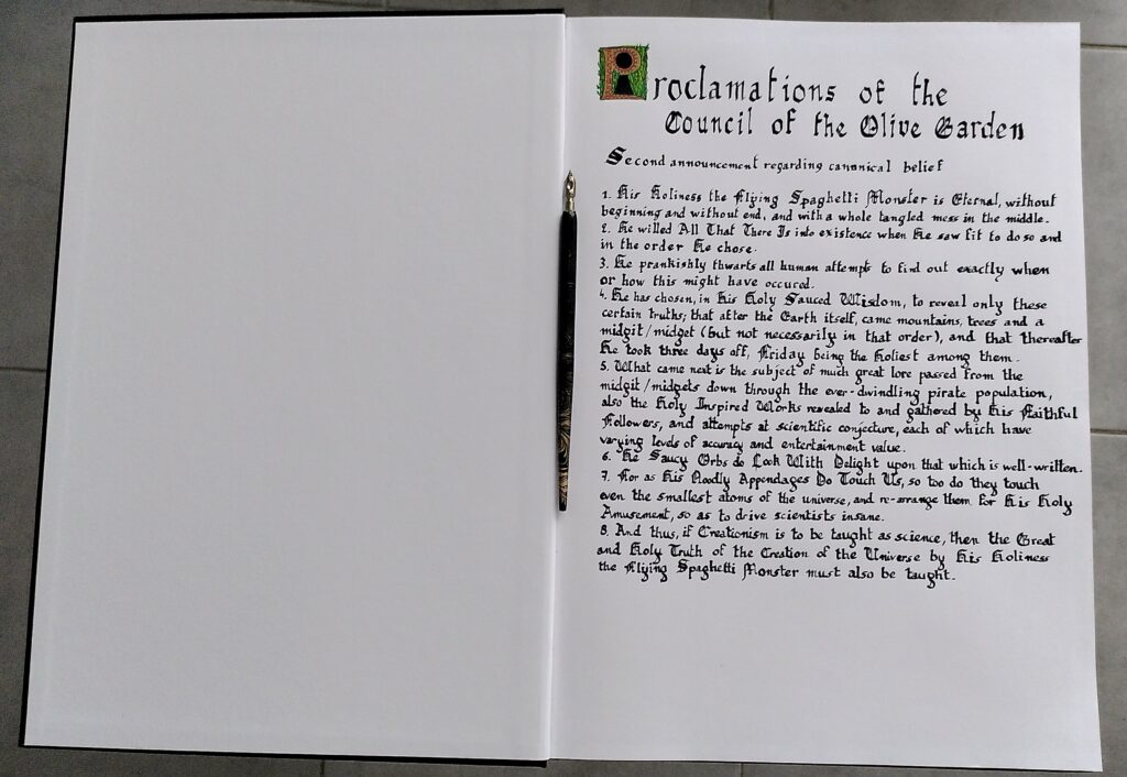 Un livre ouvert au format A3, les pages sont blanches non lignées.
La page de gauche est vierge.
La page de droite contient la première page du loose canon pastafarien, section "proclamations of the council of the olive garden".
Dans la rainure centrale, une plume est posée.